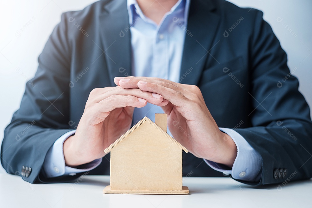 Modelo de casa de madeira da tampa da mão do empresário. conceitos imobiliários, seguros e imobiliários