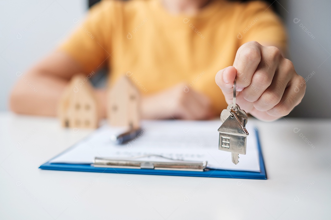 Mulher segurando a chave de casa durante a assinatura de documentos de contrato em casa. Contrato de contrato, imóveis, compra e venda e conceitos de seguros