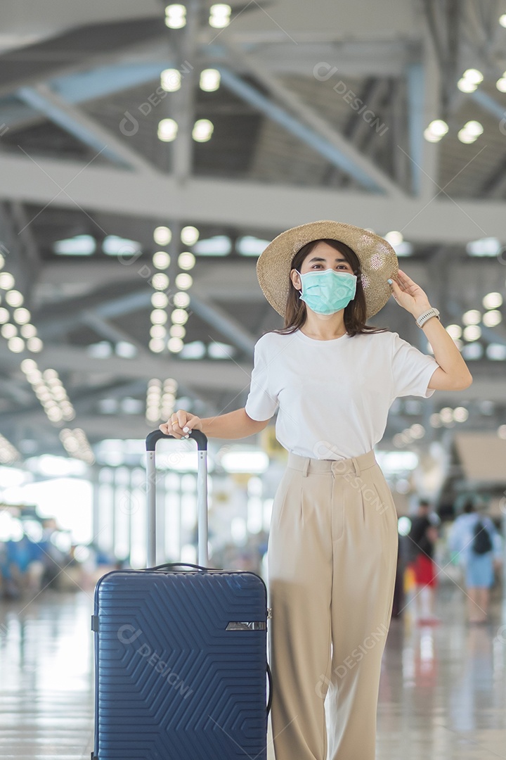 Jovem mulher usando máscara facial com bagagem andando no aeroporto, proteção contra infecção por doença de coronavírus
