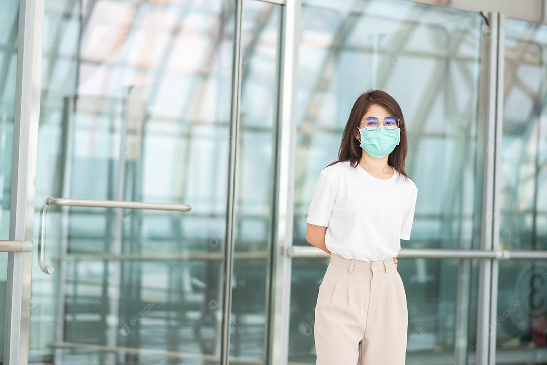 Jovem mulher usando máscara facial com bagagem andando no aeroporto, proteção contra infecção por doença de coronavírus