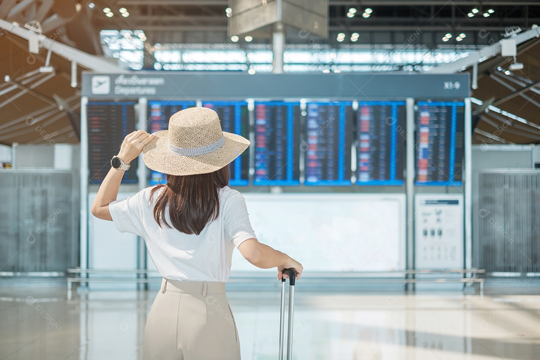 Mão de uma jovem segurando a alça da bagagem antes de verificar o tempo de voo no aeroporto, conceitos de transporte, seguro, viagens e férias