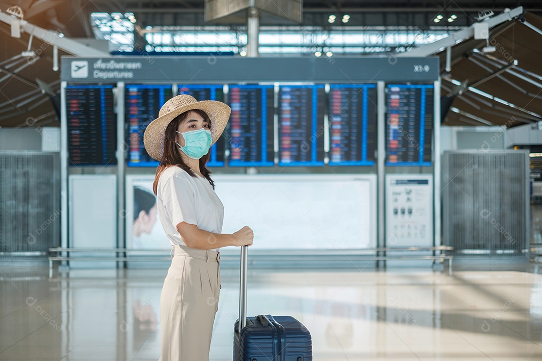 Jovem mulher usando máscara facial com bagagem andando no aeroporto, proteção contra infecção por doença de coronavírus