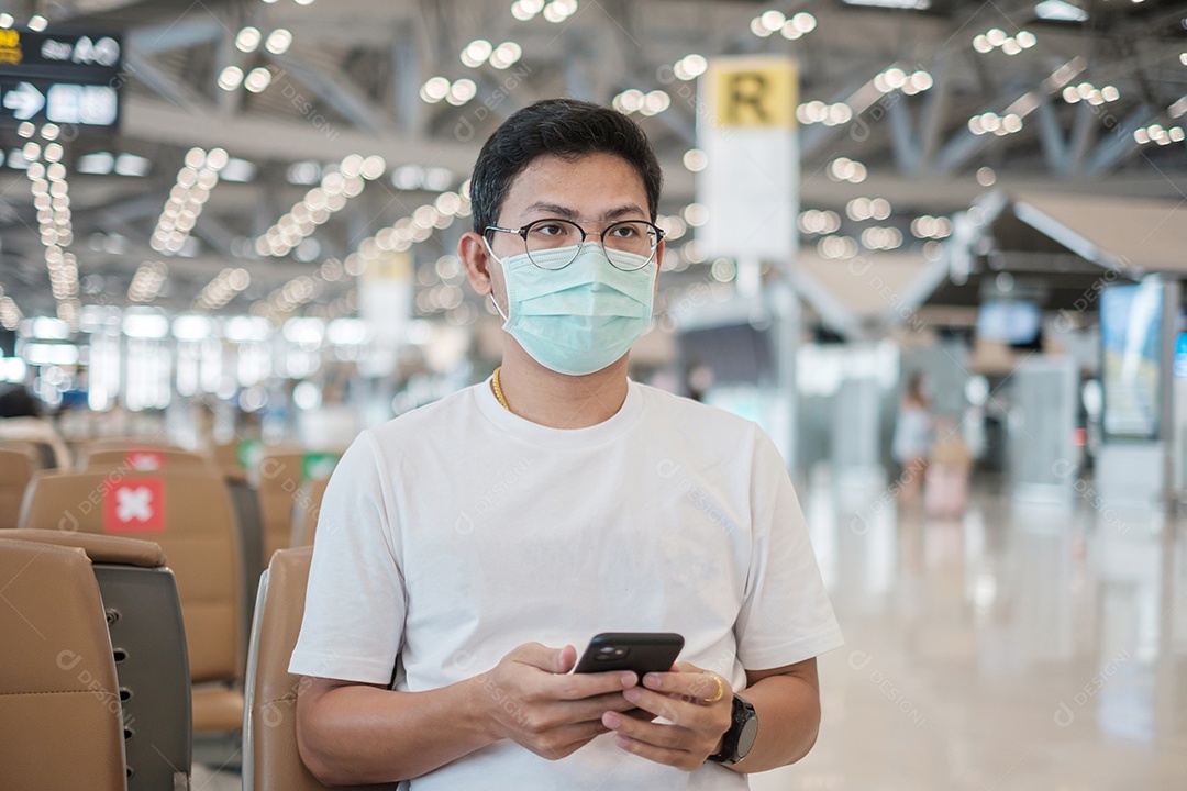 Mulher turista asiática usando máscara facial e usando smartphone móvel no aeroporto, proteção contra infecção por doença de Coronavirus.