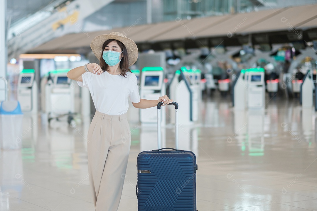 Jovem mulher usando máscara facial com bagagem andando no aeroporto, proteção contra infecção por doença de coronavírus