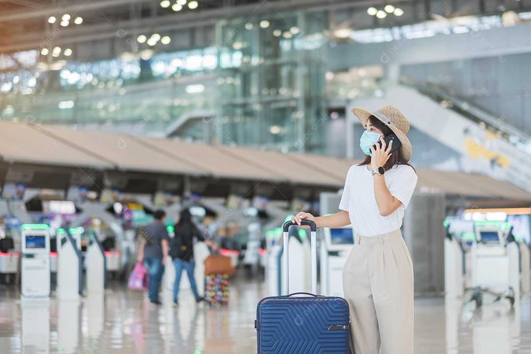 Mulher turista asiática usando máscara facial e usando smartphone móvel no aeroporto, proteção contra infecção por doença de Coronavirus