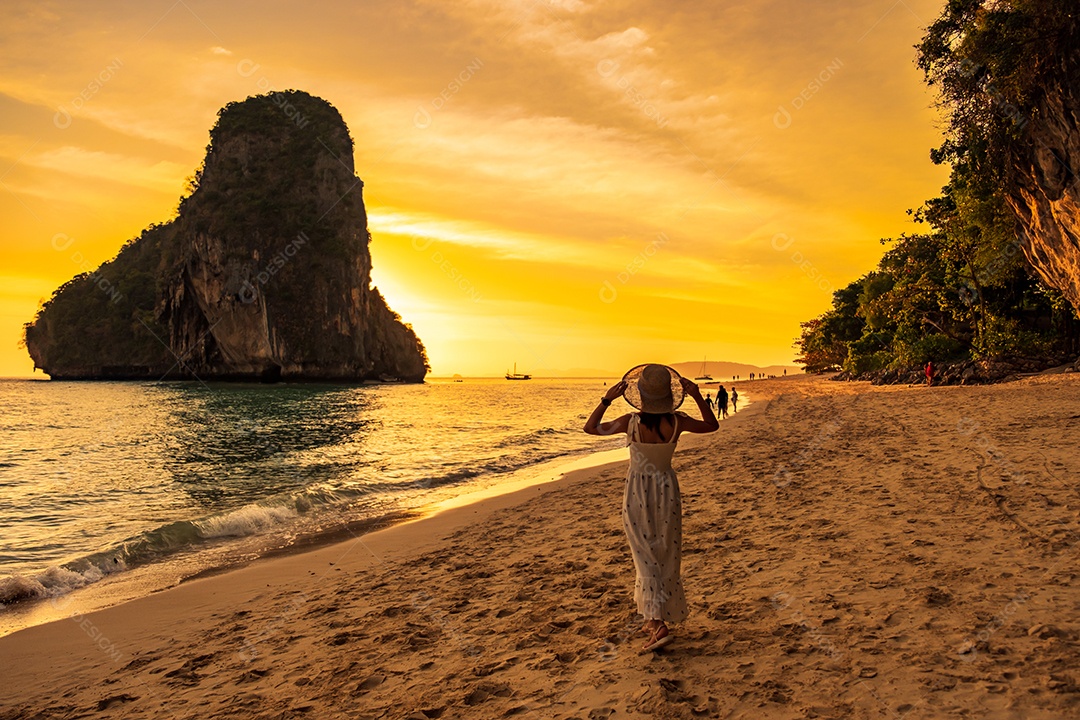 Tourist woman in white dress dining at restaurant cave on Phra nang beach at sunset, Railay, Krabi, Thailand. vacation, travel, summer, wanderlust and vacation concept