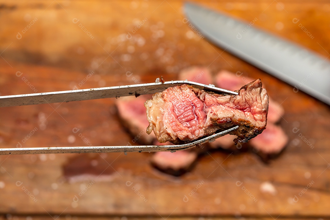 pinça de churrasco pegando carne fatiada