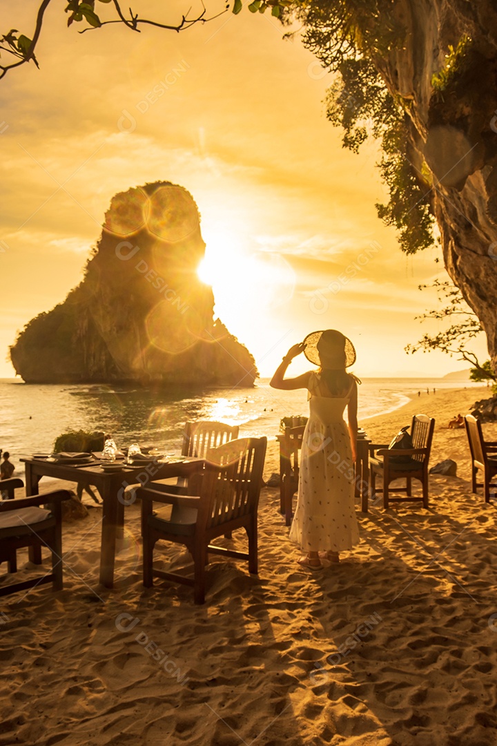 Mulher turista em jantar de vestido branco na caverna do restaurante na praia de Phra nang ao pôr do sol, Railay, Krabi, Tailândia. férias, viagens, verão, Wanderlust e conceito de férias