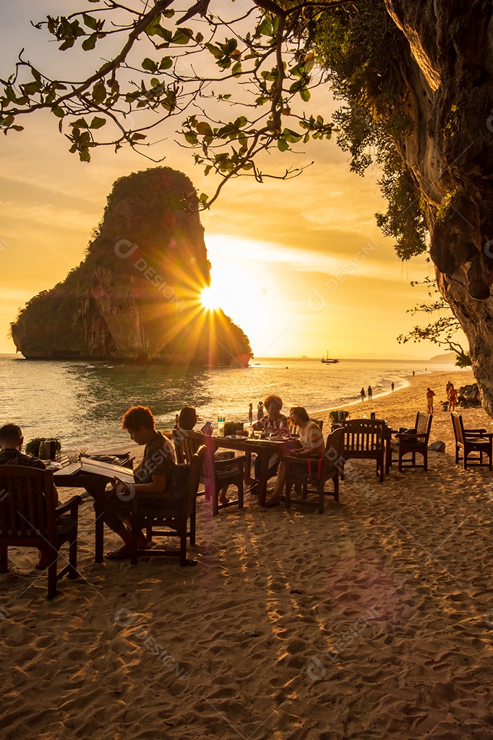 Mulher turista em jantar de vestido branco na caverna do restaurante na praia de Phra nang ao pôr do sol, Railay, Krabi, Tailândia. férias, viagens, verão, Wanderlust e conceito de férias