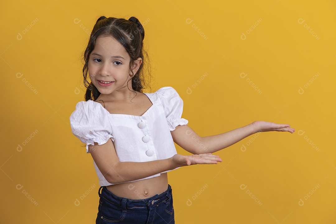Linda criança garotinha apontando para lado sobre fundo isolado amarelo