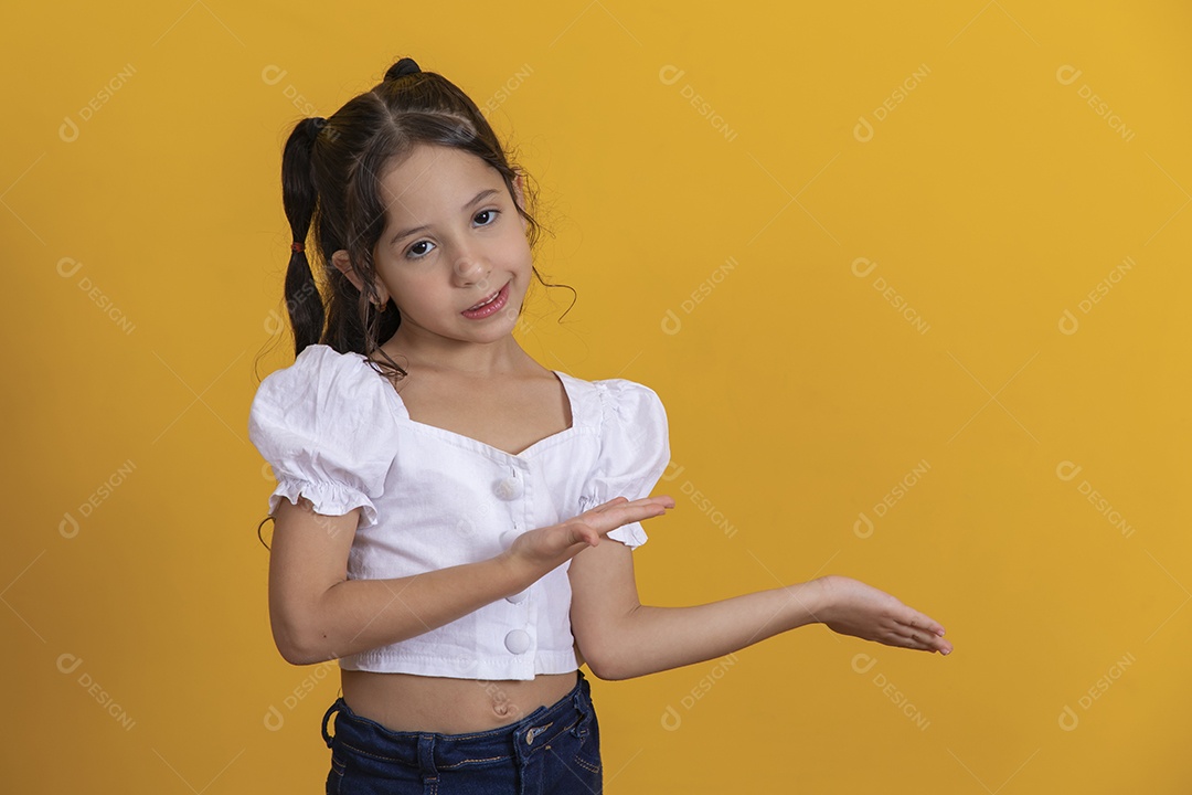 Linda criança garotinha apontando para lado sobre fundo isolado amarelo