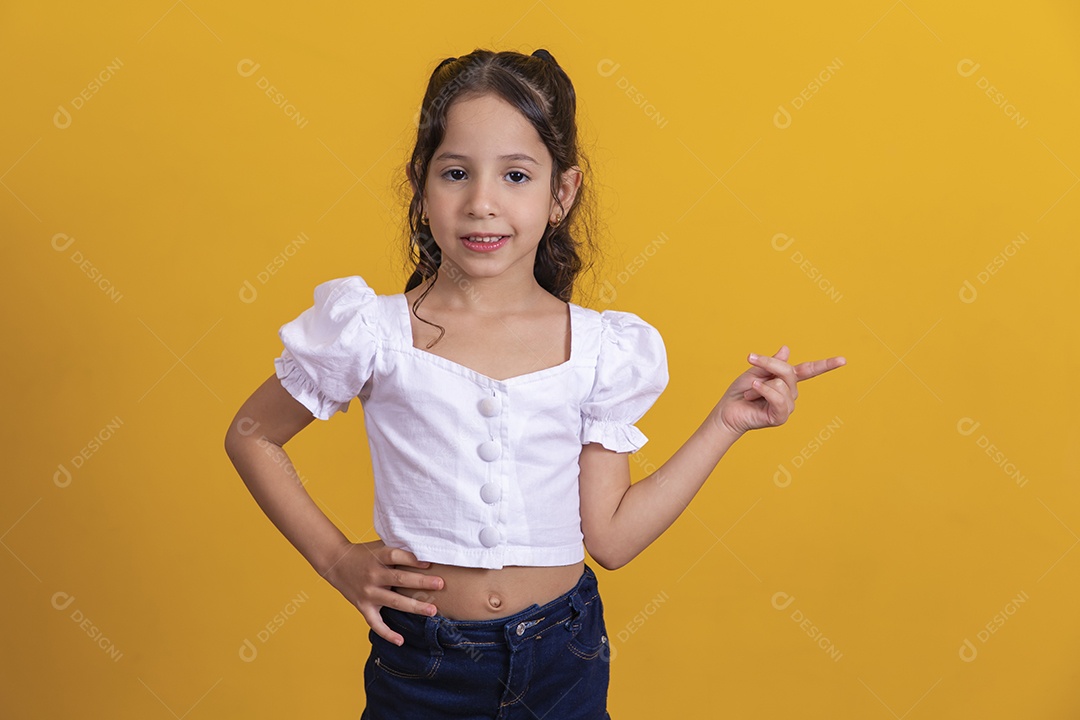 Linda criança garotinha apontando para lado sobre fundo isolado amarelo