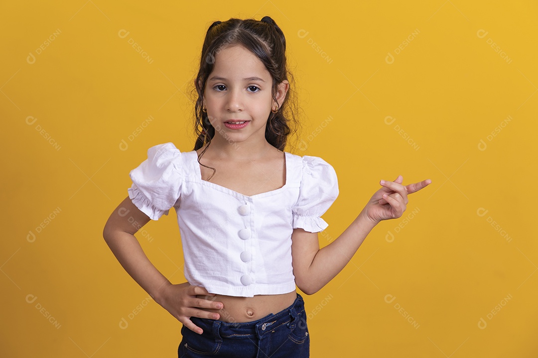 Linda criança garotinha apontando para lado sobre fundo isolado amarelo
