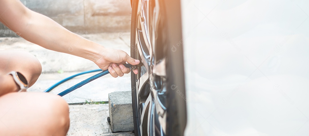 inflando manualmente os pneus do veículo, verificando a pressão do ar e enchendo o ar na roda do carro no posto de gasolina