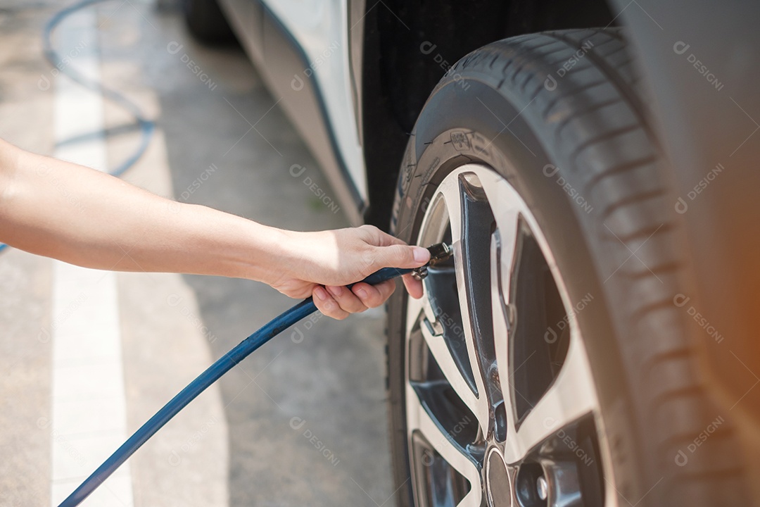 inflando manualmente os pneus do veículo, verificando a pressão do ar e enchendo o ar na roda do carro no posto de gasolina