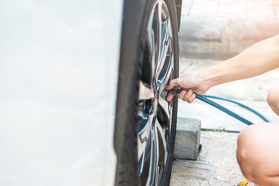 inflando manualmente os pneus do veículo, verificando a pressão do ar e enchendo o ar na roda do carro no posto de gasolina