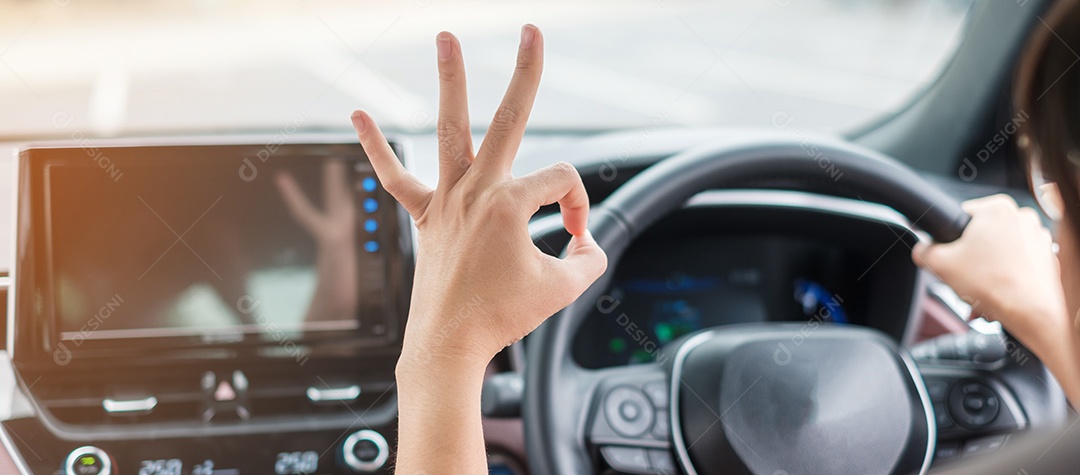 mulher mostrando sinal de OK durante a condução de um carro na estrada, volante controlando a mão no automóvel elétrico