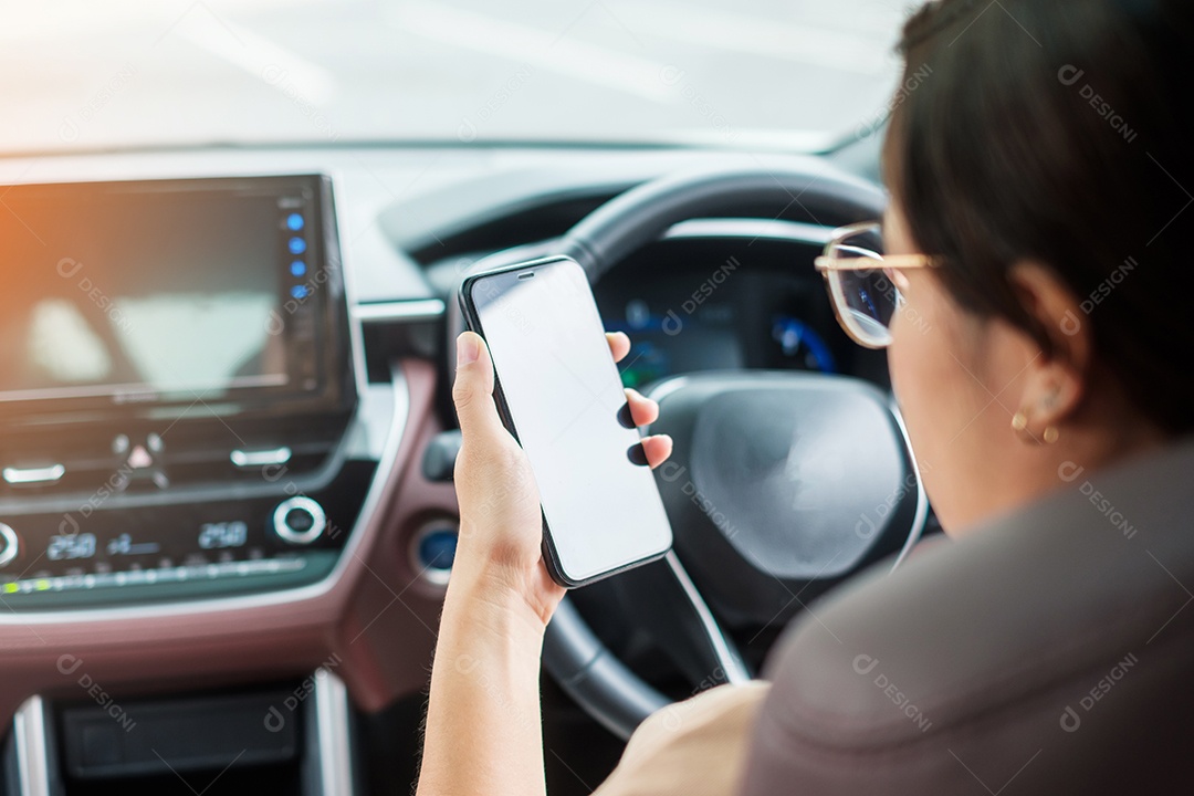 Mão de uma mulher segurando o smartphone enquanto dirigia o carro. Conceitos perigosos, viagem, viagem e transporte