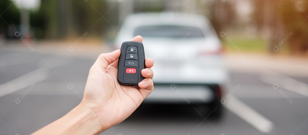 Mão segurando o controle remoto do carro, chave inteligente para bloquear ou desbloquear as portas do carro branco. Conceito de segurança, viagens e transporte