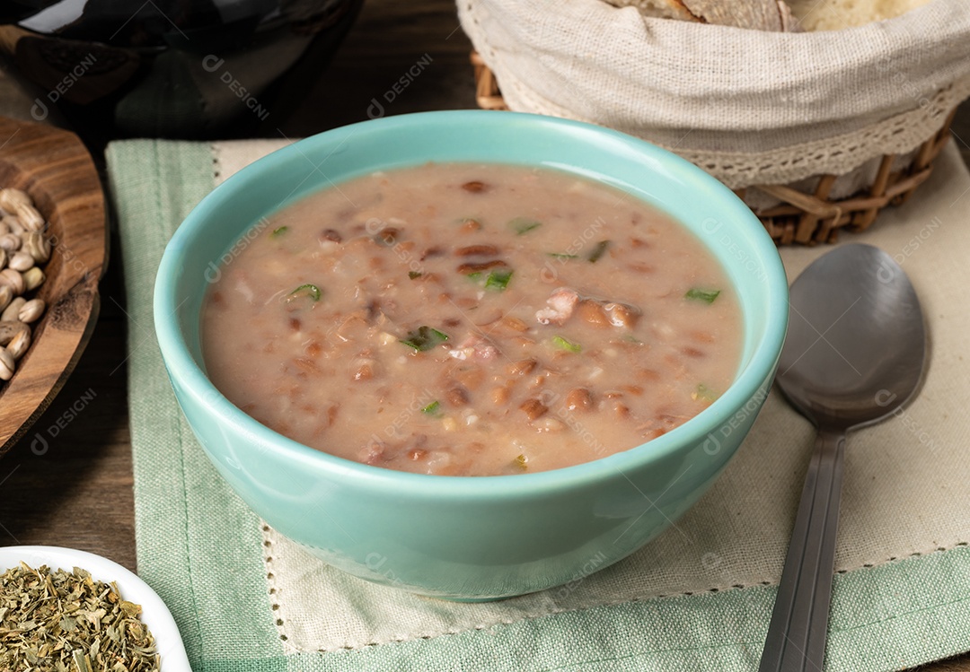 Sopa de feijão marrom em uma tigela com pão e vinho.