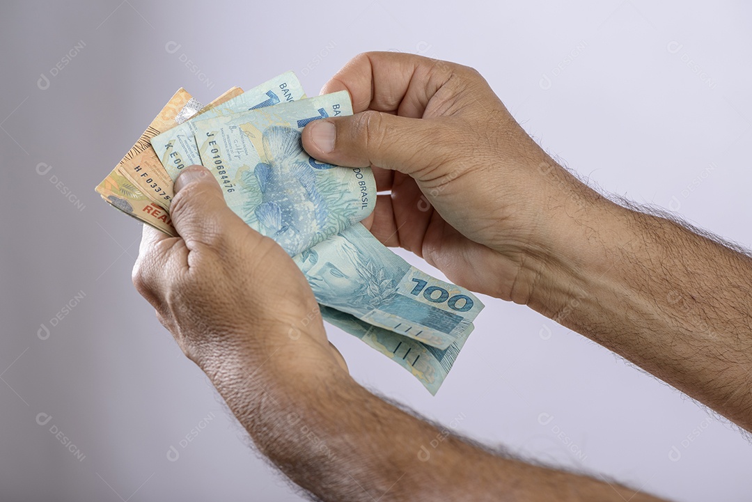 Mão segurando o dinheiro, seiscentos reais, moeda brasileira, sobre fundo branco.