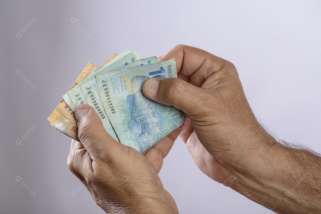 Mão segurando o dinheiro, seiscentos reais, moeda brasileira, sobre fundo branco.