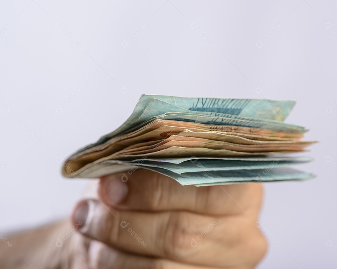 Mão segurando o dinheiro, seiscentos reais, moeda brasileira, sobre fundo branco.