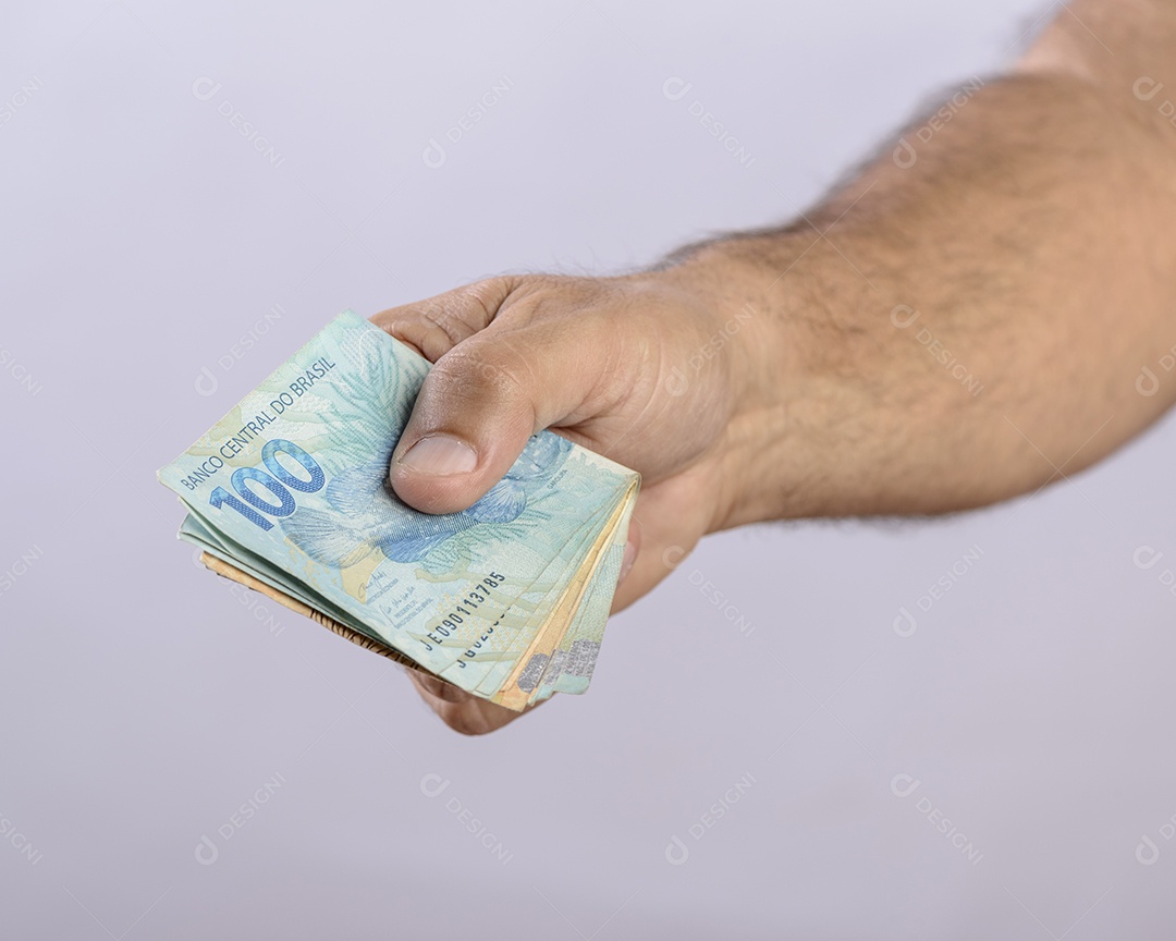 Mão segurando o dinheiro, seiscentos reais, moeda brasileira, sobre fundo branco.