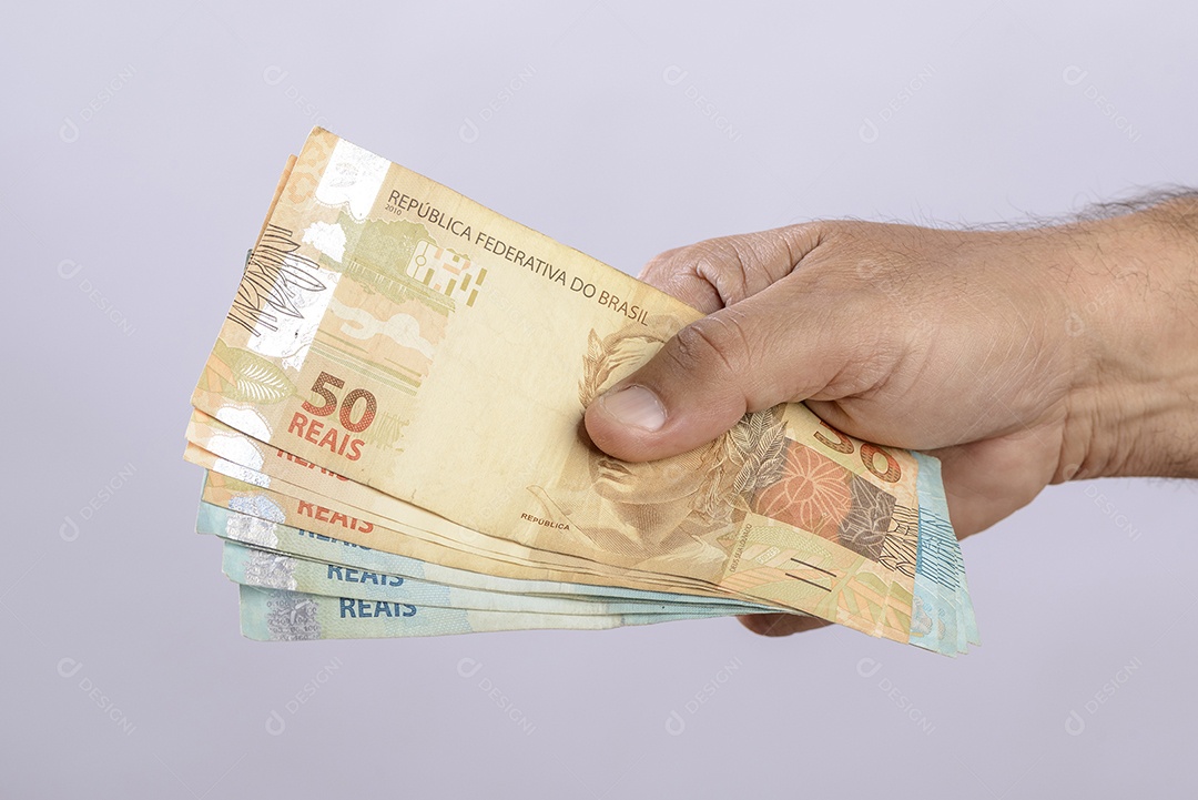 Mão segurando o dinheiro, seiscentos reais, moeda brasileira, sobre fundo branco.