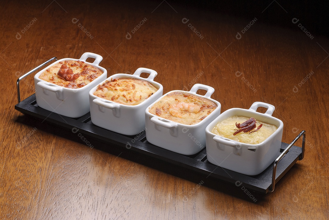 Entradas tradicionais de restaurantes brasileiros, conhecidos como escondidinho com polvo, queijo, camarão e carne.