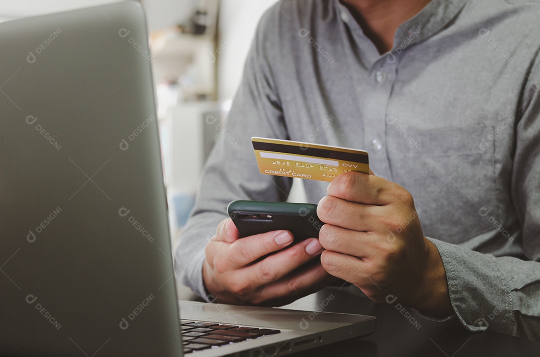 Homem segurando cartão de crédito, transação financeira ou compras online, usando marketing online de computador.