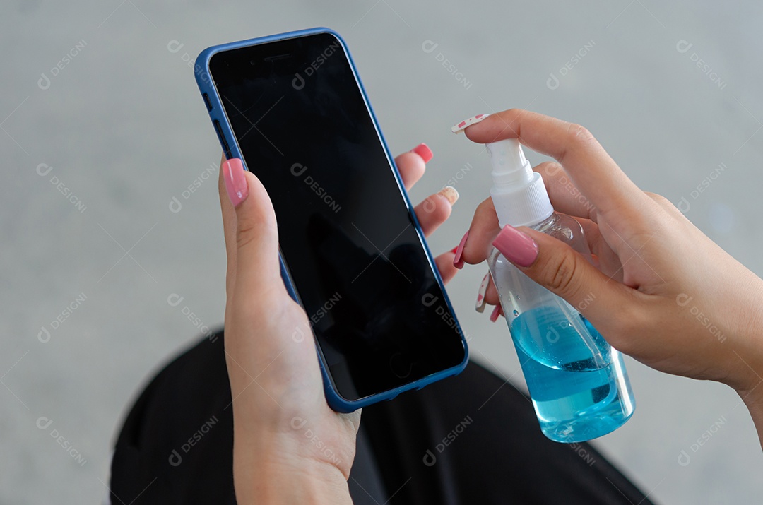 Mulher limpando e desinfetando seu celular com álcool. Conceito de cuidados de saúde para prevenir doenças
