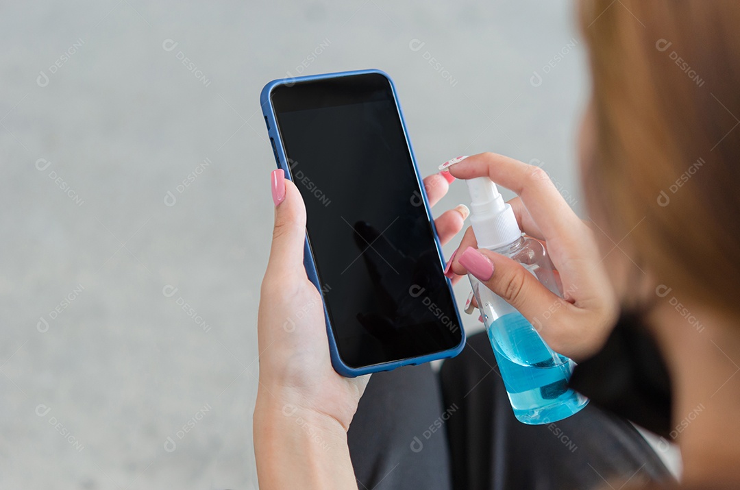 Mulher limpando e desinfetando seu celular com álcool. Conceito de cuidados de saúde para prevenir doenças