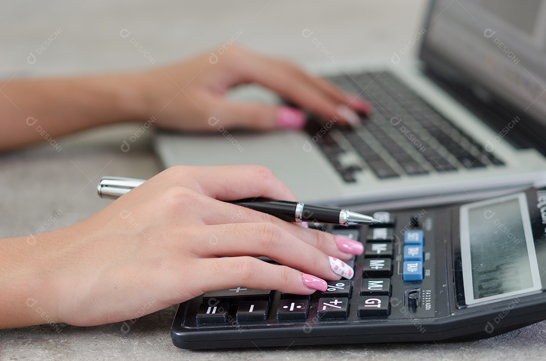 Mão de uma mulher segurando uma caneta e uma calculadora. Negócios de finanças, impostos e investimentos.