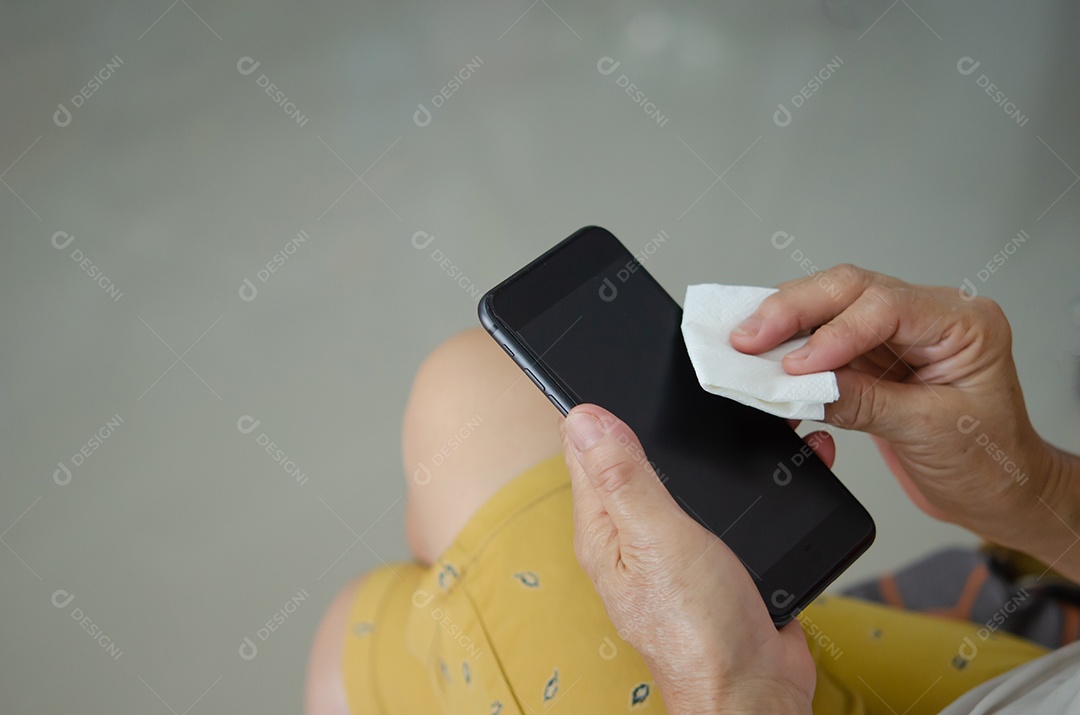 Mulher segurando telefone limpando e desinfetando seu celular com álcool. Conceito de cuidados de saúde para prevenir doenças