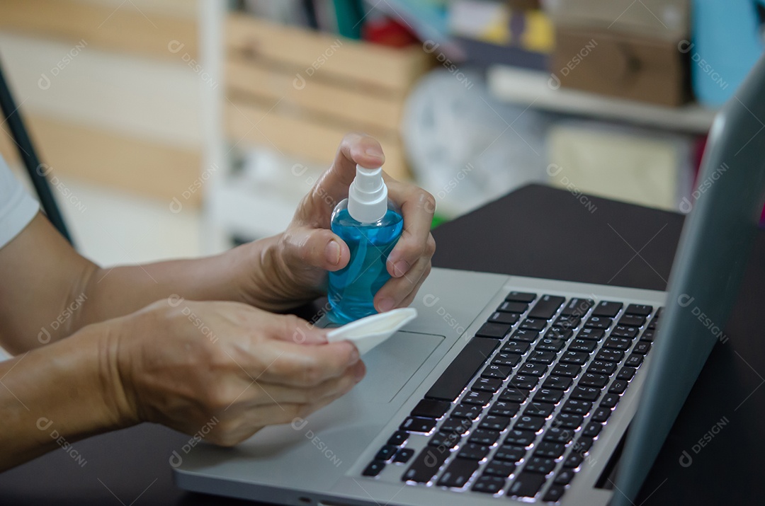 Mulher limpando e desinfetando seu notebook com álcool. Conceito de cuidados de saúde para prevenir doenças