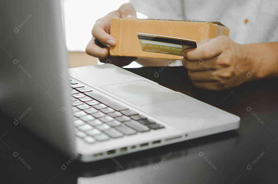 Mão de homem segurando o cartão de crédito e a caixa de encomendas. Conceito de negócio de compras online.
