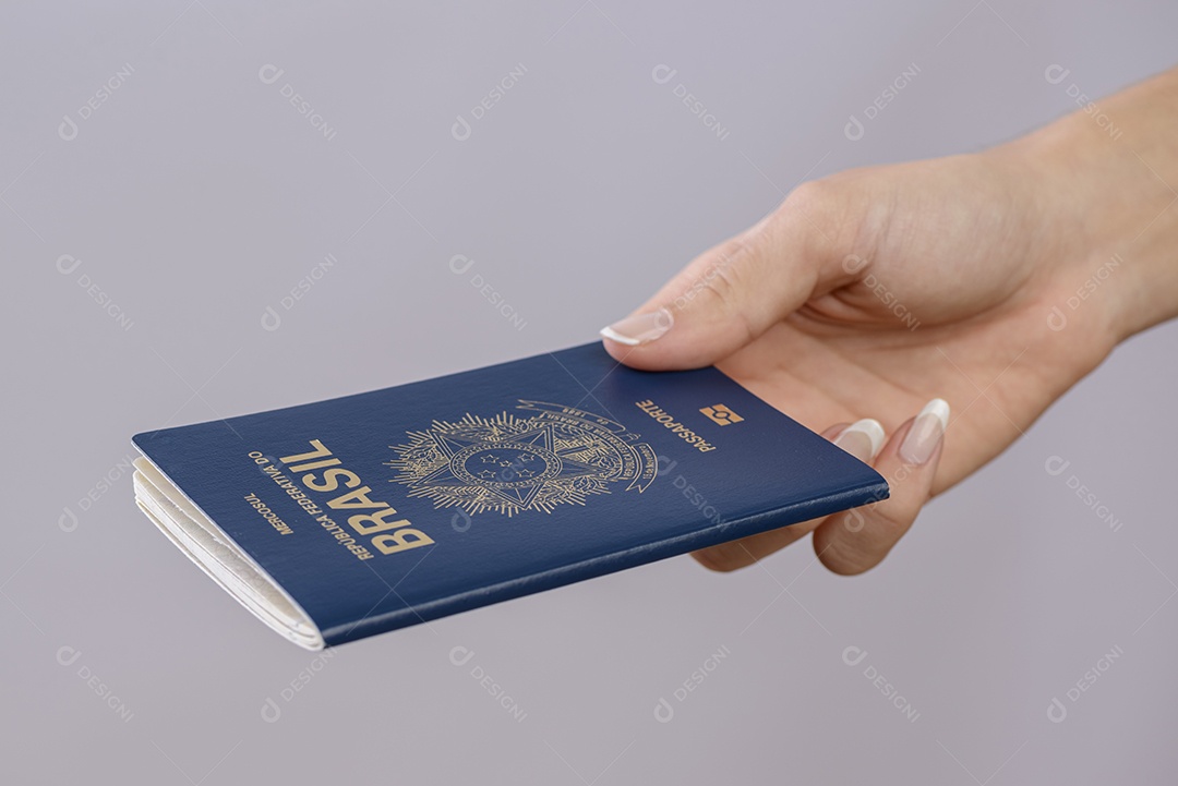 Passaporte brasileiro em uma mão com fundo branco.
