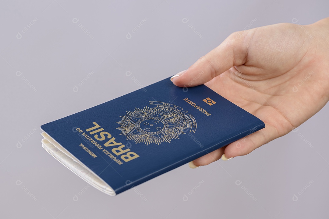 Passaporte brasileiro em uma mão com fundo branco.