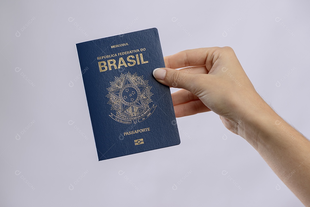 Passaporte brasileiro em uma mão com fundo branco.