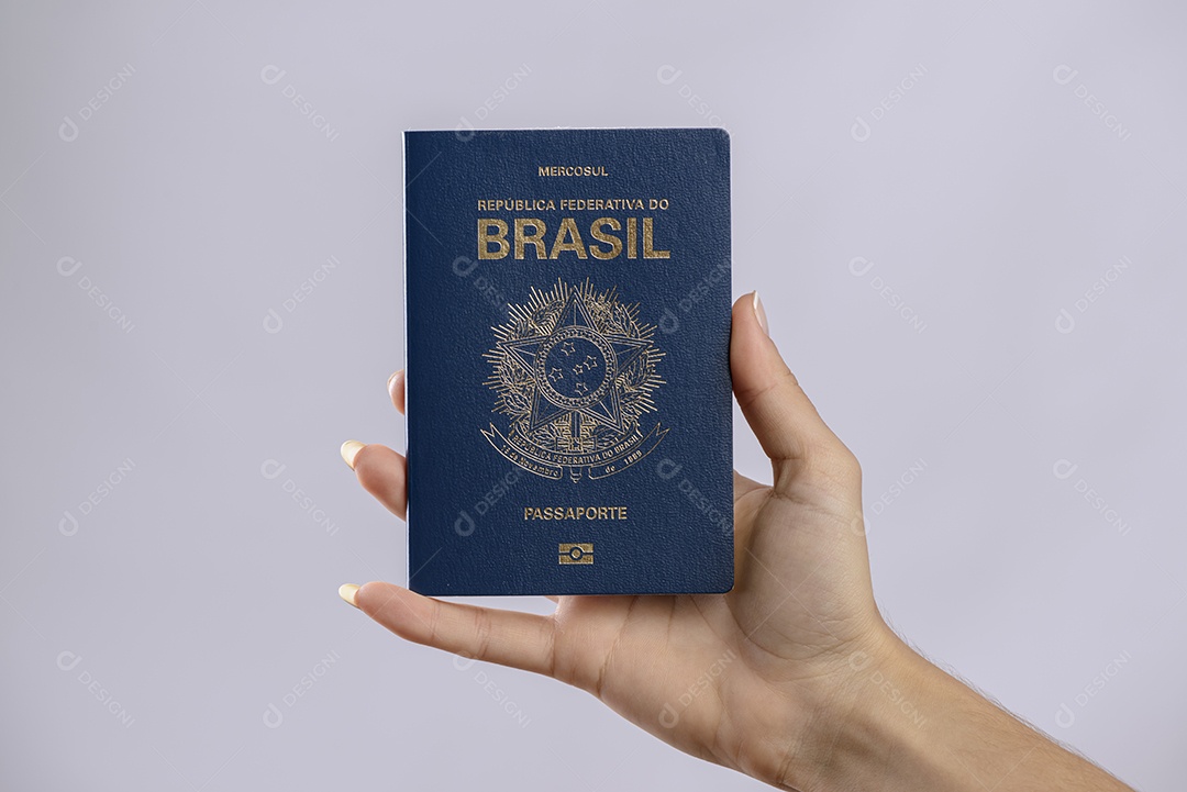 Passaporte brasileiro em uma mão com fundo branco.