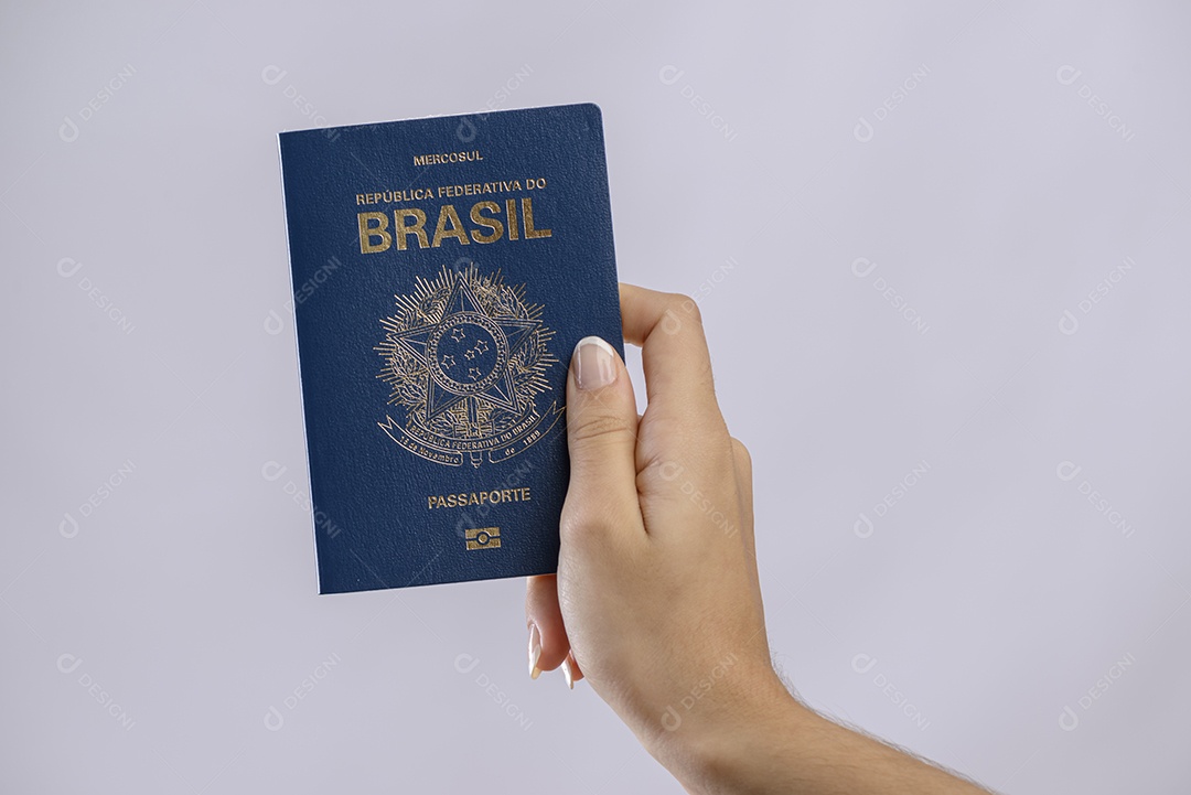 Passaporte brasileiro em uma mão com fundo branco.