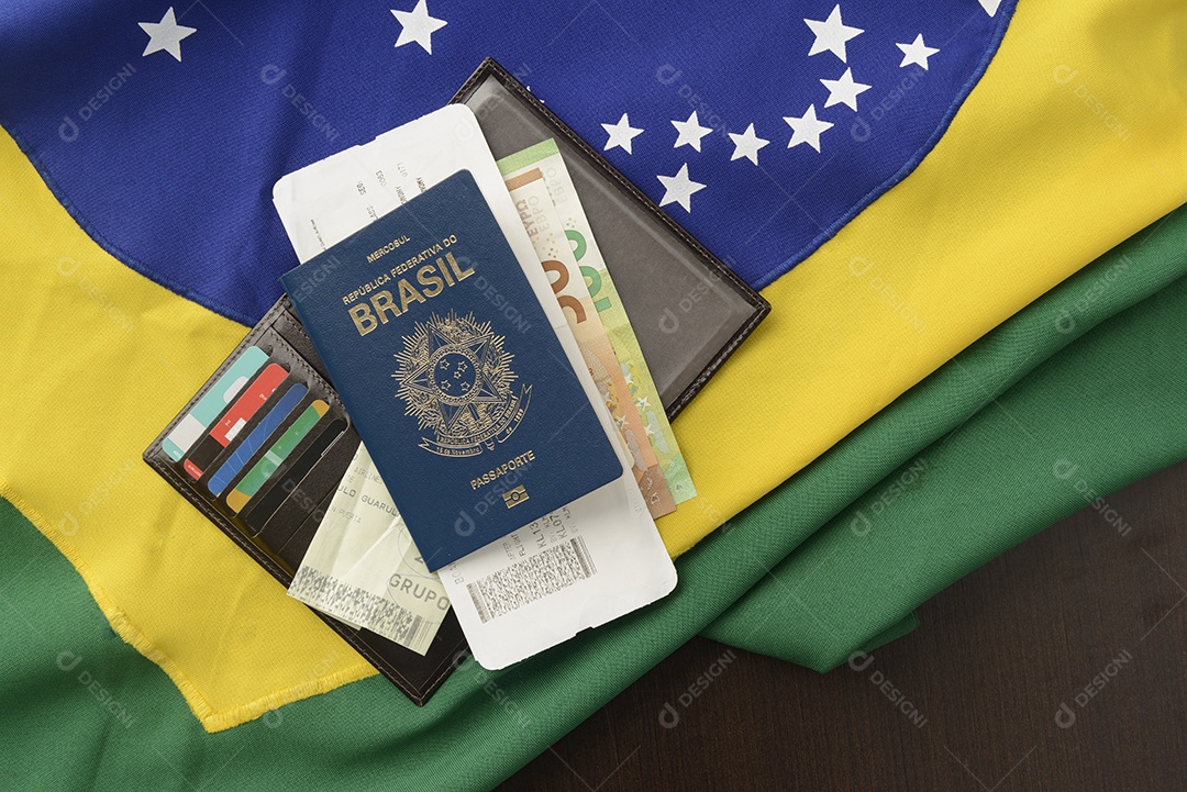 Passaporte brasileiro sobre mesa com bandeira brasileira ao fundo.