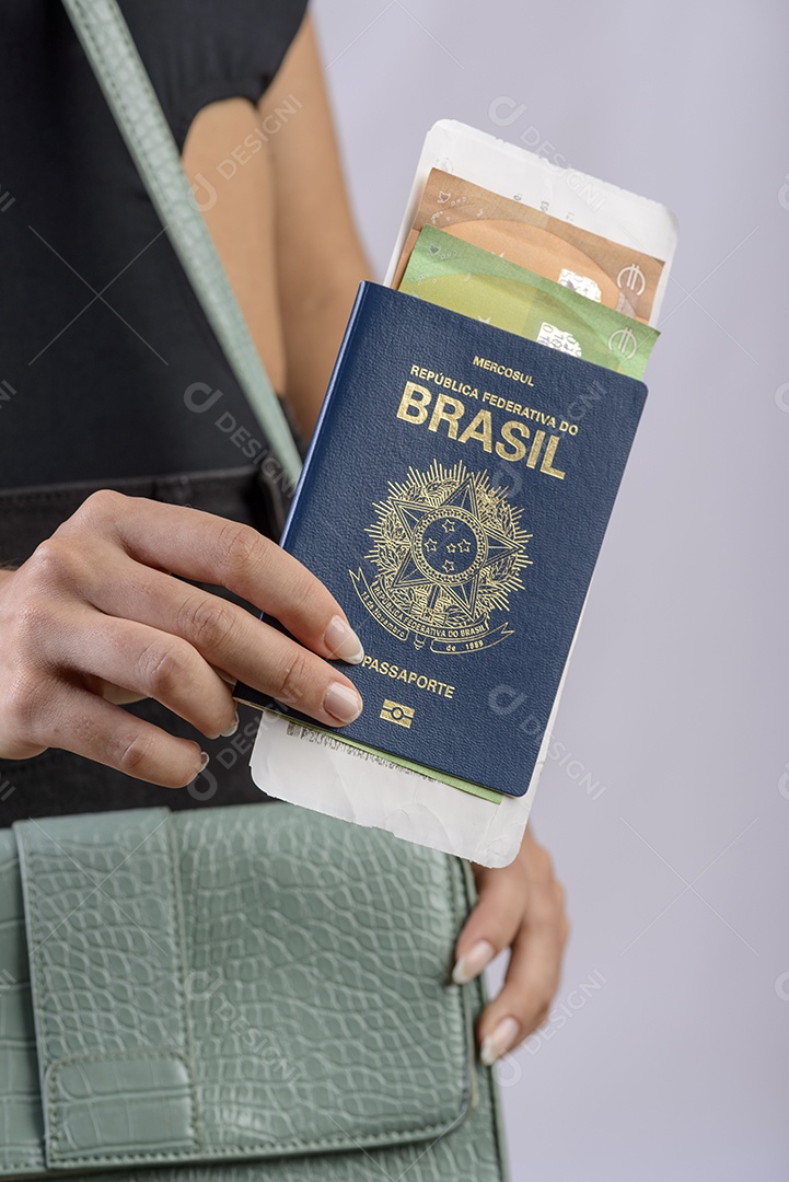 Passaporte brasileiro. Mãos colocando passaporte brasileiro na bolsa feminina verde.