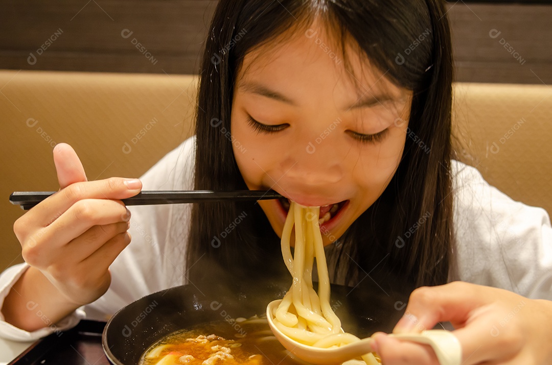 Menina asiática comendo comida japonesa