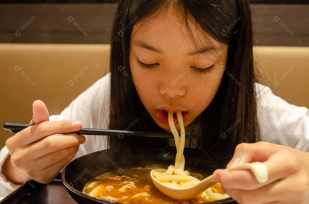 Menina asiática comendo comida japonesa