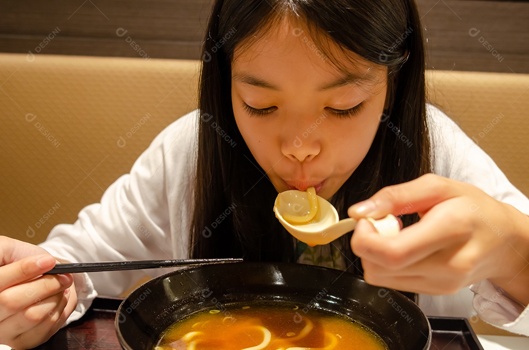 Menina asiática comendo comida japonesa