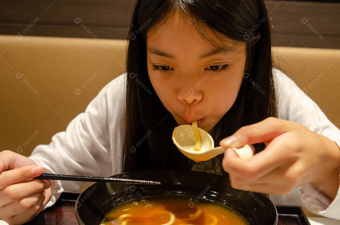 Menina asiática comendo comida japonesa