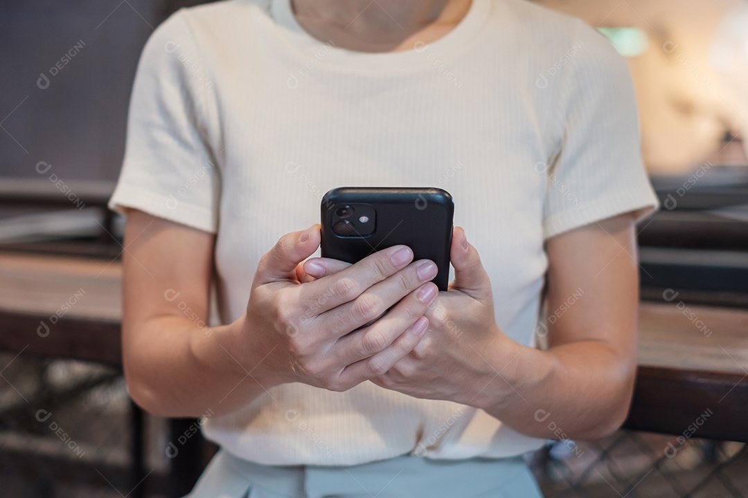 Mulher de negócios casual segurando e usando smartphone para mensagens sms, jovem digitando celular touchscreen no café ou escritório moderno. estilo de vida, tecnologia, mídia social e conceito de rede