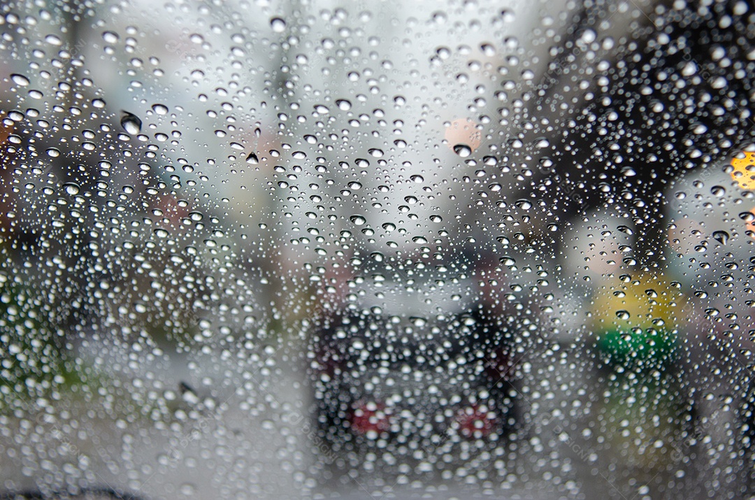 Janela do carro com gotas de chuva dirigindo na chuva fundo de engarrafamento desfocado